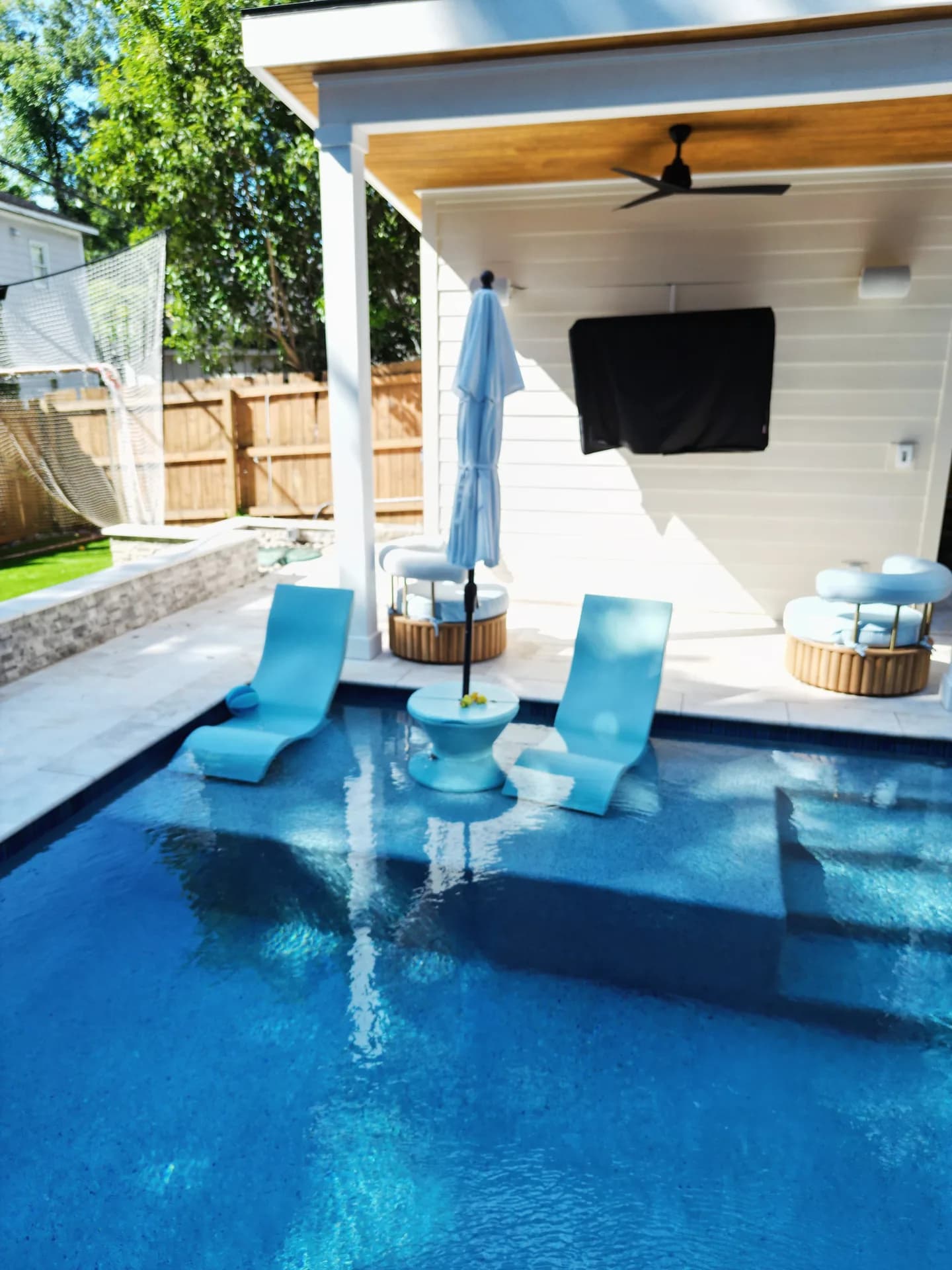 Two aqua loungers and a small table on a pool sun shelf beside a covered patio in Patriot’s Charlotte-area project
