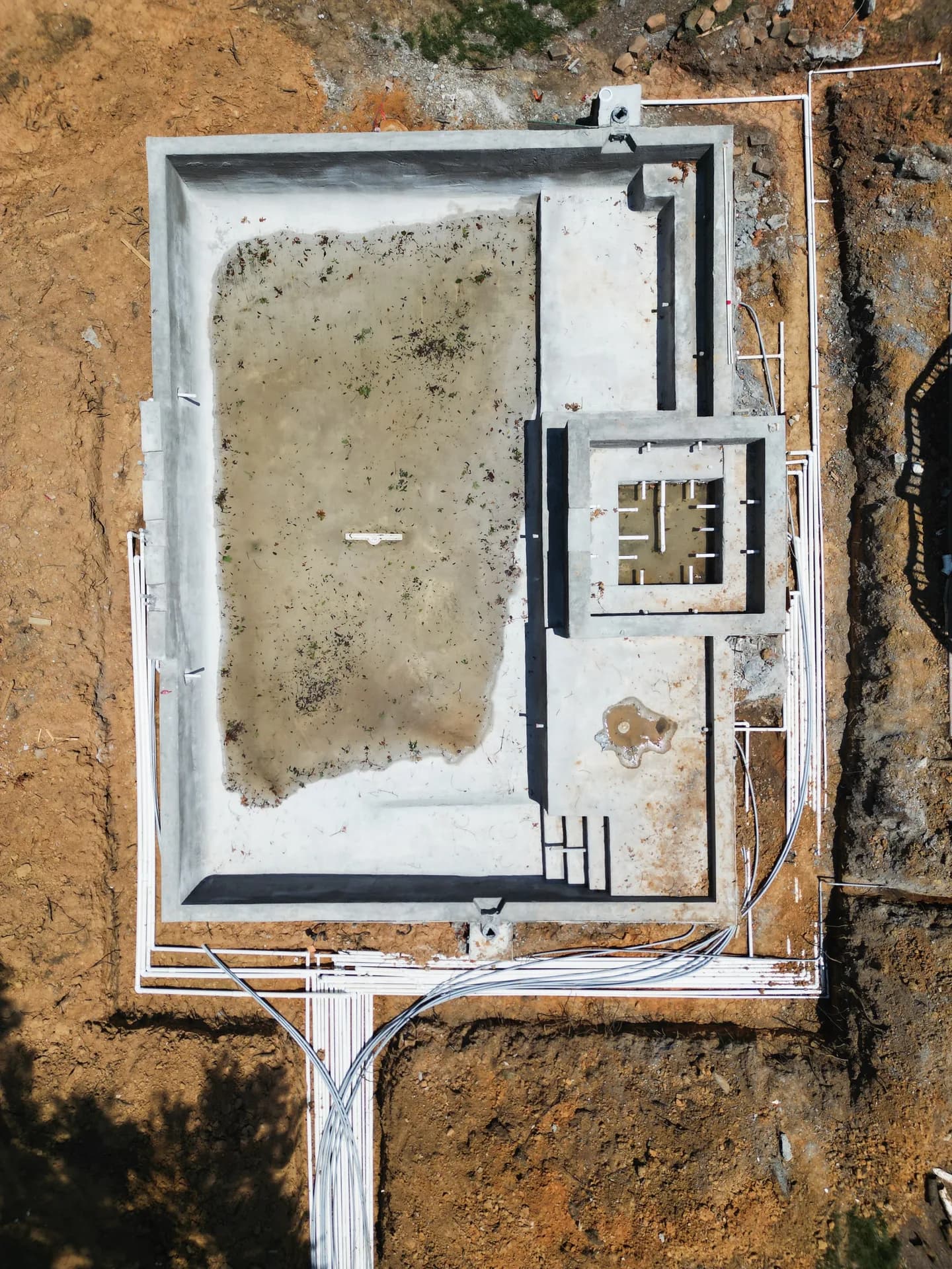 Overhead view of a Patriot pool and adjoining spa during construction, with surrounding pipe runs visible