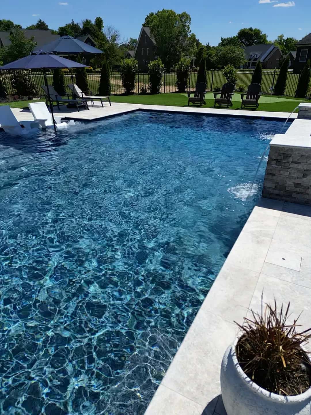 A rectangular pool has in-water seating on one side and water streams entering from a raised wall.